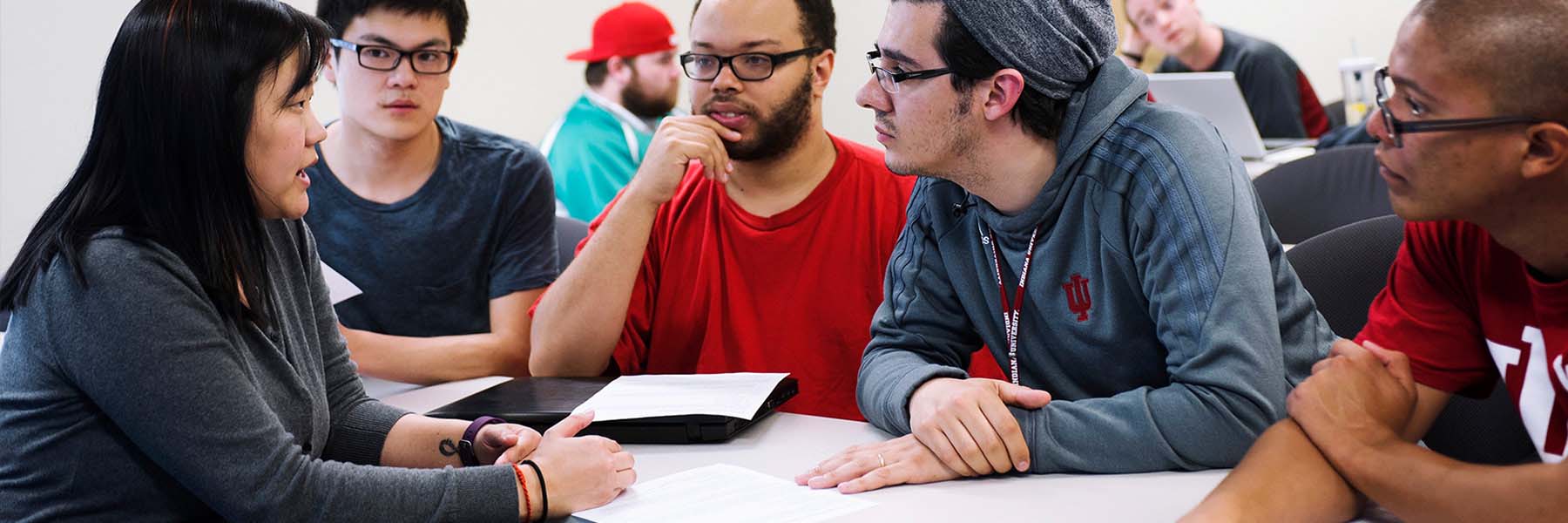 Four students listen intently to a faculty member.